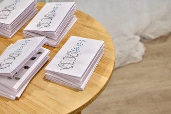 Stack of small publications sit on a round plinth, image is cropped on left
