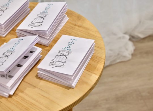Stack of small publications sit on a round plinth, image is cropped on left